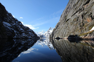 Trollfjorden kledd i vinterdrakt på speilblankt hav. Foto: Adventure Tailor.
